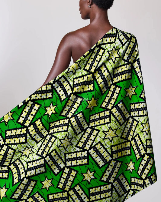 Person draped in a green and yellow patterned fabric with stars on a plain background