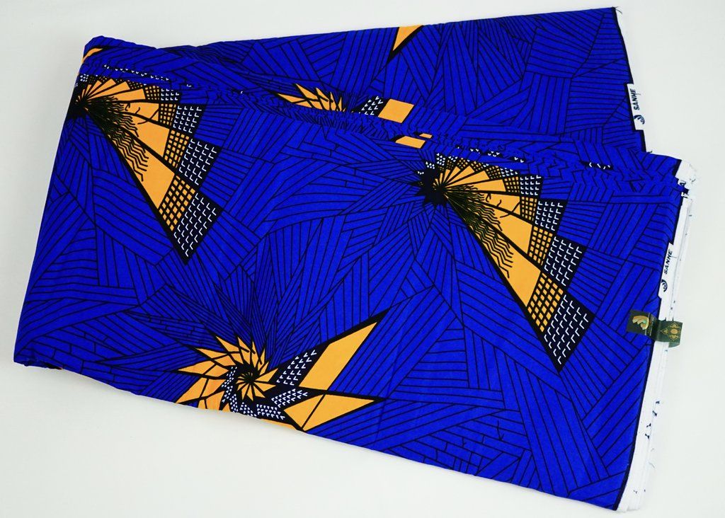 Royal blue Ankara wax print with orange starbursts, laid out