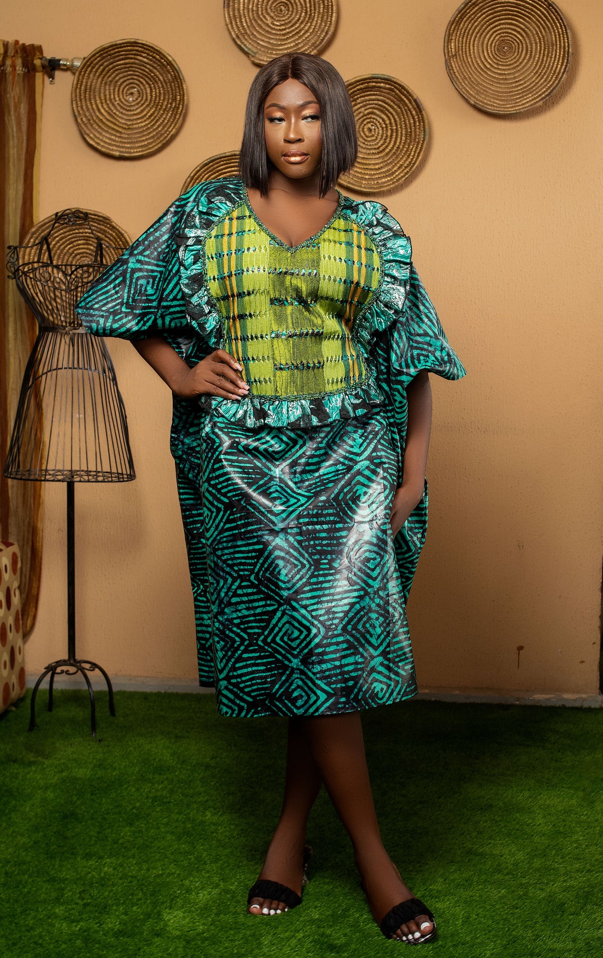 Fashion inspiration: a model wearing a teal patterned dress in a warm studio.