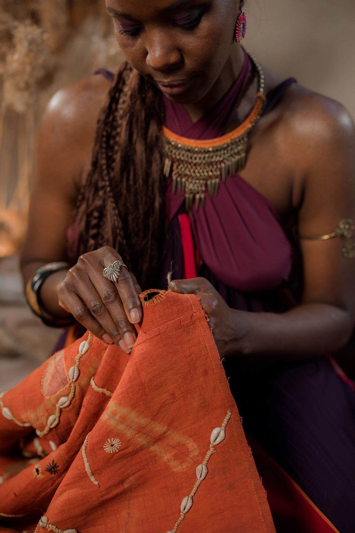 A maker hand-stitching an orange textile, photographed by cottonbro studio.