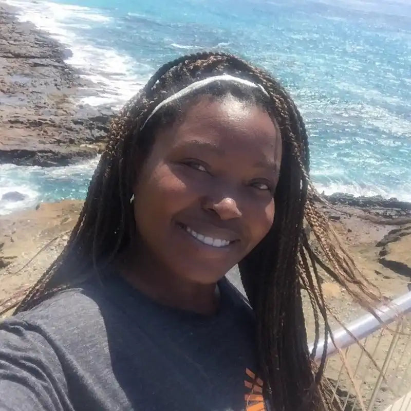 A smiling woman with long braided hair and a white headband.